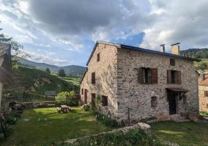 un vieux bâtiment en pierre sur une colline avec une table dans l'établissement Chalet familiale de montagne - Pyrénées-Orientales, à Puyvalador