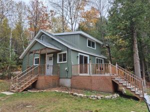 a green house with a staircase in the woods at Chalet lac Chantelle in Chertsey