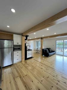 a large living room with wooden floors and a kitchen at Chalet lac Chantelle in Chertsey