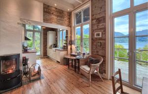 a living room with a fireplace and a table and chairs at Beach Front Home In Vaksdal With House Sea View in Stavenesli