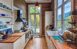 a kitchen with white cabinets and a large window at Beach Front Home In Vaksdal With House Sea View in Stavenesli
