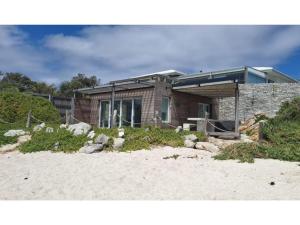 a house sitting on top of a sandy beach at Pringle Bay Villa in Pringle Bay