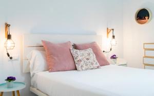 Un dormitorio con una cama blanca con almohadas rosas. en Alohamundi Rocío, en Sevilla