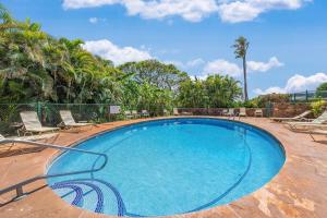 a large blue swimming pool with chairs and palm trees at Kaanapali Plantation 10 · KPL 10 Panoramic Ocean Views 2BD near in Lahaina