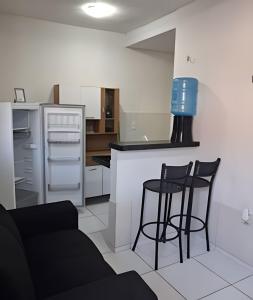 a kitchen with two black bar stools and a refrigerator at Apartamento acolhedor Maracanaú -Premium in Maracanaú