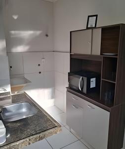 a kitchen with a sink and a microwave on a counter at Apartamento acolhedor Maracanaú -Premium in Maracanaú