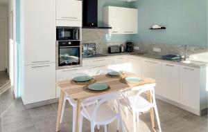 a kitchen with a wooden table and white cabinets at Lovely Home In Jard Sur Mer With Wifi in Jard-sur-Mer