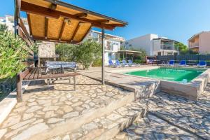 a swimming pool with a table and a bench next to a house at House Osti in Rogoznica