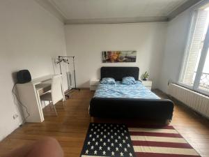 a bedroom with a bed and a desk with a flag rug at Paradeux - Chambre dans grande Maison Gite sur Argenteuil, Parking dans cour securisée, pour ouvriers ou groupes de travailleurs in Argenteuil