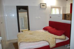 a bedroom with a red bed with a blanket and a mirror at Il Moraiolo - Casale Piccolo in Pigge