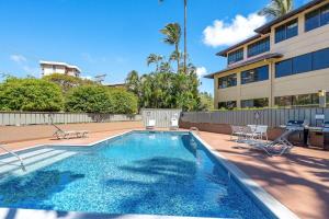 Una piscina con sillas y un edificio. en Kahana Manor 608 · KMN 608 Partial Ocean Views from 2BD Kahana C, en Kahana