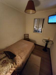 a bedroom with a bed and a table and a tv at Ven tranquilo al MOVISTAR ARENA in Santiago