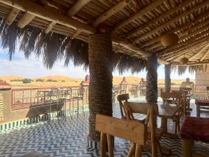 a patio with tables and chairs and a view of the desert at Kasbah Azalay Merzouga takojt in Merzouga