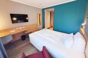 Una habitación de hotel con una cama, un escritorio y un televisor. en Garner Hotel Cottbus Süd by IHG, en Cottbus