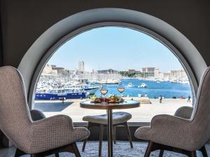 a table with glasses of wine in front of a window at Grand Hotel Beauvau Marseille Vieux-Port - MGallery Collection in Marseille
