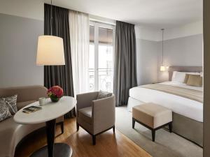 une chambre d'hôtel avec un lit, une table et une chaise dans l'établissement Sofitel Paris Arc De Triomphe, à Paris