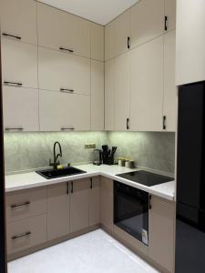 a kitchen with white cabinets and a black sink at Luxury Apartment at Nest One Residence in Tashkent +4 photos