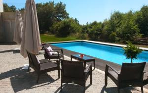 a swimming pool with chairs and an umbrella and a table at Equinaturi in Santo Tirso