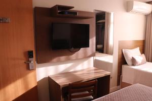 a hotel room with a tv and a small desk at Vida Plaza Hotel in Brasília
