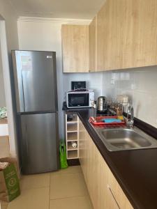 a kitchen with a stainless steel refrigerator and a sink at Cómodo departamento in El Tabo