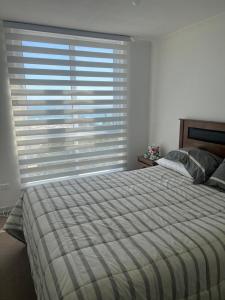 a bedroom with a bed and a window with blinds at Cómodo departamento in El Tabo