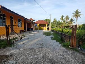 an empty road in front of a house with a gate at Homestay Teratak Senja in Pasir Mas