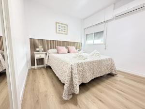 a white bedroom with a bed with pink pillows at The Coastal Pearl - Beachfront 2 BR Apartment with Balcony in Fuengirola +4 photos