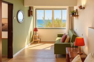 a living room with a green couch and a window at Seaview Ensuite rooms in Sagres centre - Casa Maluka in Sagres