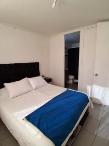 Un dormitorio con una cama grande con una manta azul. en Departamento Parque O'Higgins, en Santiago 4 fotos más