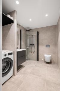 ein Badezimmer mit Waschmaschine und Toilette in der Unterkunft Moderne leilighet i Vannkunsten Syd in Oslo