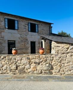 Una casa de piedra con dos macetas en una pared. en Casa Arxemil, en Sarria