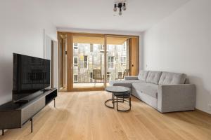 ein Wohnzimmer mit Sofa und Fernseher in der Unterkunft Moderne leilighet i Vannkunsten Syd in Oslo