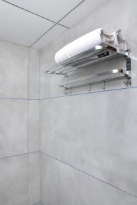 a bathroom with white walls and a shelf with towels at Hotel Pine View in Rajkot