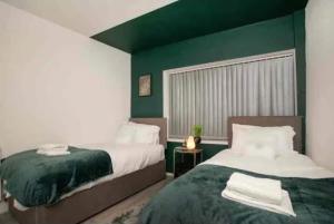 1 Schlafzimmer mit 2 Betten und einer grünen Wand in der Unterkunft Base is a lovely place to unwind after a long day in Wincobank