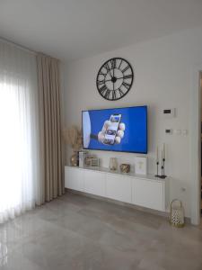 a living room with a tv and a clock on the wall at Apartman City Pearl in Posušje