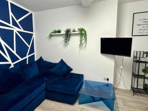 ein Wohnzimmer mit einem blauen Sofa und einem Fernseher in der Unterkunft Base is a lovely place to unwind after a long day in Wincobank