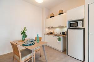 a kitchen with a table and a white refrigerator at Résidence de Perros-Guirec in Perros-Guirec