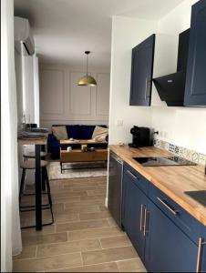 a kitchen with blue cabinets and a living room at Charmant Studio Balneo wifi clim borne electrique in Vierzon