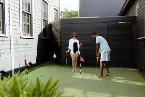 a man and a woman playing golf on a putting greens at Blackbird Hotel in New Orleans