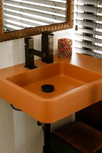 een oranje wastafel in een badkamer met een raam bij Brut Loft Caminha in Caminha