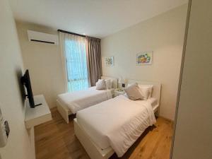 a hotel room with two beds and a window at FAMILY HOMES Halo - Brand New 2BDRM Poolside Apartment in Phuket