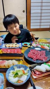 un enfant assis à une table avec des assiettes de nourriture dans l'établissement Villa 峰々, à Fujikawaguchiko