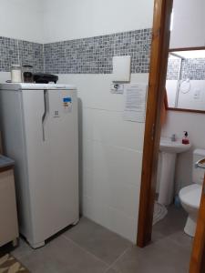 a small kitchen with a refrigerator and a toilet at Recanto do Sol Pousada in Capão da Canoa