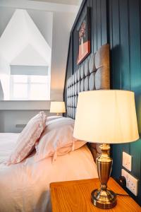 ein Schlafzimmer mit einem Bett und einem Tisch mit einer Lampe in der Unterkunft The Raven Pub with Rooms in Claines