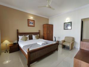 a bedroom with a bed and a chair in it at Ora Stays by Q 23 - Near to Fortune Select Candolim in Candolim +25 photos