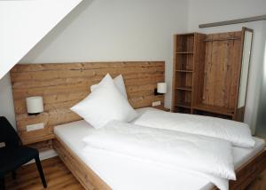 ein Schlafzimmer mit einem weißen Bett mit einem hölzernen Kopfteil in der Unterkunft Gästehäusle in Mundelsheim in Mundelsheim