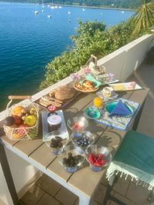 a picnic table with baskets of food on a table near the water at BB les pieds dans L'eau CARANTEC in Carantec
