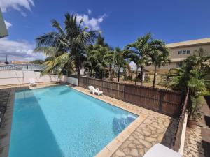 a swimming pool with a fence and palm trees at Studio Amorisca Peaceful 2-Person Stay in Flic-en-Flac