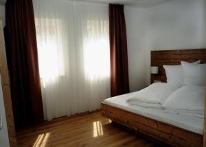 ein Schlafzimmer mit einem Bett mit weißen Laken und einem Fenster in der Unterkunft Gästehäusle in Mundelsheim in Mundelsheim