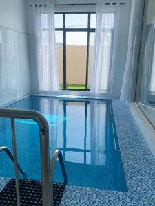 una piscina de agua azul en una habitación con ventana en شالية همس الفاخرة, en Taif